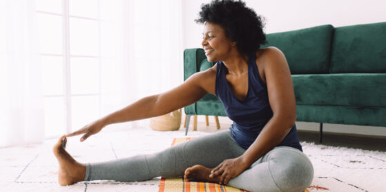 African woman doing exercise at home. Mature woman doing stretching workout in living room.